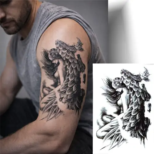 Tatouage ange temporaire gris et noir appliqué sur le haut du bras, motif réaliste et éphémère, parfait pour tester un tatouage avant un engagement permanent.