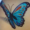 Tatouage éphémère papillon pailleté bleu, avec un design scintillant. Facile à appliquer, ce tatouage apportera une touche colorée à votre style.