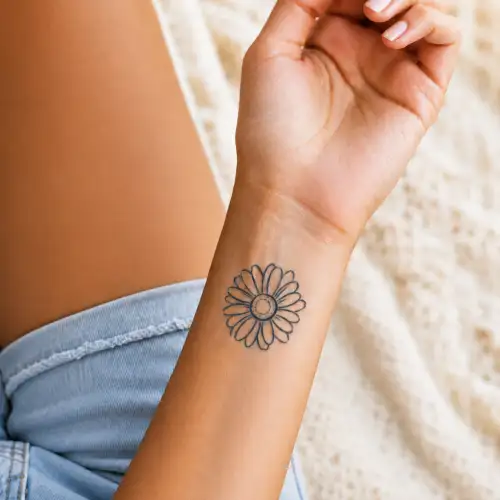 Tatouage marguerite au jagua semi-permanent bleu nuit de 5 cm appliqué sur le poignet d'une femme, effet réaliste et waterproof.