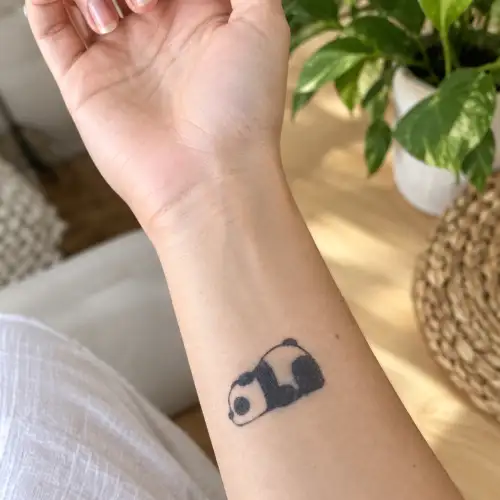Petit tatouage panda noir au jagua sur l’avant-bras, motif semi-permanent à effet réaliste