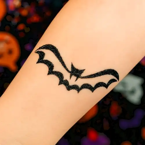 Tatouage éphémère en paillettes représentant une chauve-souris, créé avec un pochoir adhésif et de la colle cosmétique, idéal pour les animations enfants et les fêtes d’Halloween.