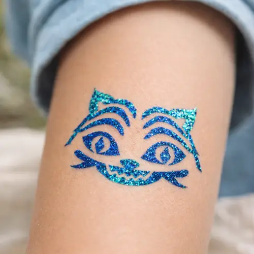 Tatouage pailleté représentant une tête de chat, réalisé avec un pochoir adhésif, de la colle cosmétique et des paillettes, inspiré d’un univers pop culture et manga.