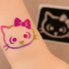 Tatouage temporaire scintillant en forme de tête de chat avec un nœud.