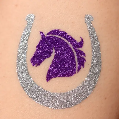 Tatouage paillette en forme de fer à cheval réalisé avec un pochoir adhésif, de la colle cosmétique et des paillettes scintillantes.