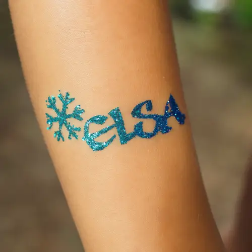 Tatouage pailleté reine des glaces, réalisé avec un pochoir et des paillettes bleu turquoise et bleu roi.