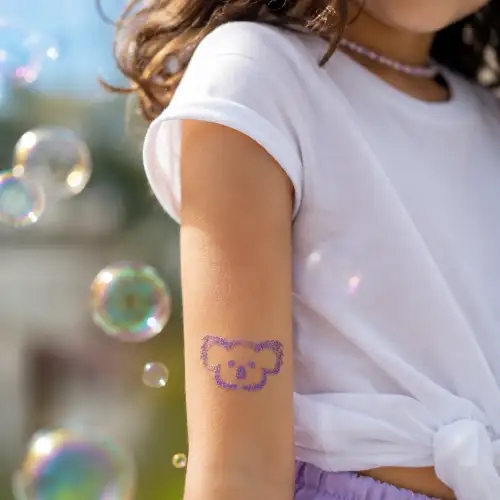 Tatouage pailleté koala violet scintillant appliqué sur le bras d'un enfant.