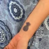 Tatouage temporaire semi-permanent ananas au jagua, design tropical, effet bleu nuit naturel, durée de 8 à 15 jours.
