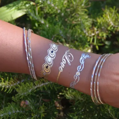 Tatouages éphémères dorés – motifs métallisés brillants, parfaits pour sublimer les peaux bronzées en été.